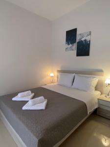 a bedroom with a large bed with two towels on it at Villa Erdeti Studio & Apartment in Sarandë