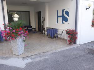 un portico anteriore con fiori e un cartello k su un edificio di Hotel Serenella a Lido di Jesolo