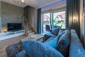 a living room with a blue couch and a tv at Rydzewo domek w zabudowie szeregowej nad jeziorem in Rydzewo