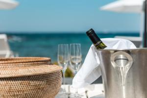a bottle of wine in a bucket on a table with wine glasses at Apollo Resort in Agia Marina Aegina