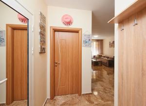 a hallway with a wooden door and a living room at Апартаменти "Лазур" в сърцето на Поморие in Pomorie