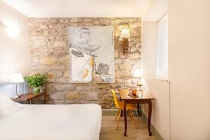 サン・セバスティアンにあるHotel Okako San Sebastianの石壁のベッドルーム(テーブル、ベッド付)