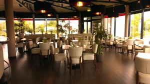 a restaurant with white chairs and tables and windows at Plaza Inn Berlin Süd Ludwigsfelde in Ludwigsfelde