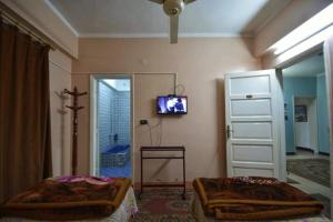 a bedroom with two beds and a tv on the wall at Fontana Hostel luxor in Luxor