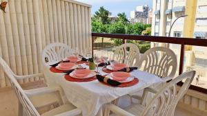 stół z białymi krzesłami i różowymi naczyniami w obiekcie SALINAS CENTRO - PLAYA DE GANDIA w mieście Playa de Gandia