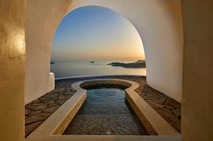 une arche menant à une piscine avec vue sur l'océan dans l'établissement Petit Palace Suites, à Fira