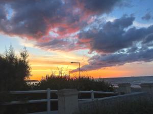 una puesta de sol sobre el océano con una valla blanca en Villa lumineuse en front de mer - Gold Beach, en Asnelles