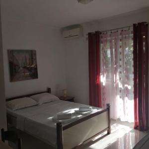 Apartments Muhar في سفيتي ستيفان: غرفة نوم بسرير ونافذة ذات ستائر حمراء