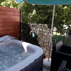 una vasca idromassaggio in un cortile con ombrellone di LA TERRASSE AUX HIRONDELLES maison 80m2 2 chambres 2 salles de bains a Lagorce