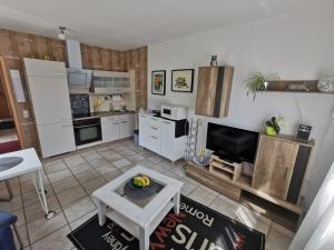 a kitchen with white cabinets and a tv in a room at Ferienwohnung Emma in Konz