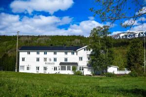a white building in a field with a mountain at Rundhaug Gjestegard in Rundhaug