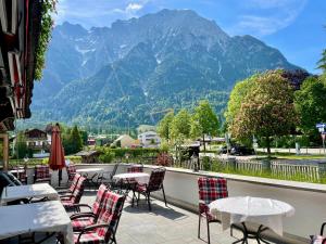 een patio met tafels en stoelen met bergen op de achtergrond bij Gästehaus Sonnenheim in Mittenwald