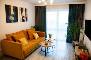 salon z żółtą kanapą i stołem w obiekcie APARTAMENT BIESZCZADY w mieście Ustrzyki Dolne