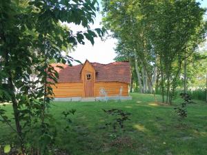 une cabane en rondins au milieu d'une cour arborée dans l'établissement La Gare de Lurey Conflans gîte et hébergements insolites en Champagne, à Esclavolles-Lurey