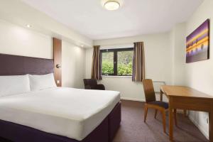 a hotel room with a bed and a desk at Days Inn Kendal - Killington Lake in Kendal