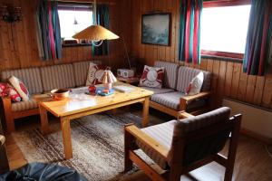 a living room with couches and a wooden table at Fjøset in Hansnes