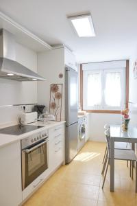 a white kitchen with a table and a stove top oven at Peregrina Pension 3 in O Pedrouzo