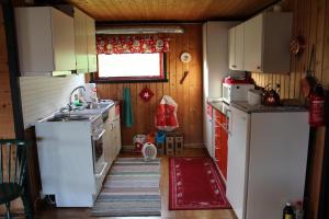 una pequeña cocina con electrodomésticos blancos y una ventana en Fjøset, en Hansnes