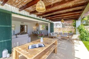 a patio with a wooden table and a couch at Villa Conguitos in Sant Lluis +40 photos