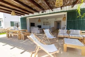 a patio with chairs and tables and a couch at Villa Conguitos in Sant Lluis