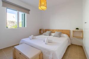 a bedroom with a large white bed and a window at Villa Conguitos in Sant Lluis