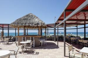 コッキニ・カニオンにあるGolden Bay Boutique Hotel & Bungalowsのテーブルと椅子、藁の傘が備わるレストラン
