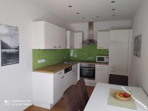 a kitchen with white cabinets and a table with a bowl of fruit at Appartementhaus Lisa in Afritz