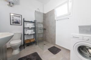 a bathroom with a toilet sink and a washing machine at Lazaris Apartments in Almiros Beach