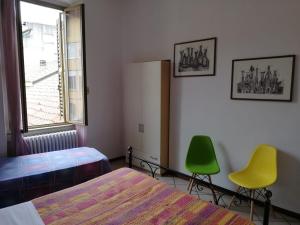a bedroom with two beds and two green chairs at B&B Smeraldo Airport in Bergamo