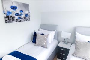 - une chambre avec 2 lits dotés d'oreillers bleus et blancs dans l'établissement Park Cottage Willows Riverside Park, à Windsor