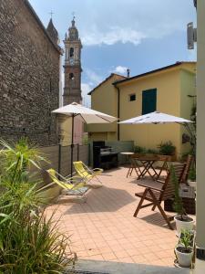 un patio con sillas y sombrillas y una torre de reloj en The Old Mansion, en Vasia