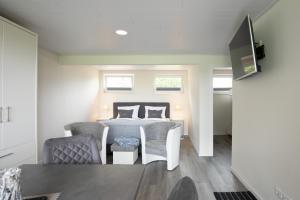 a bedroom with a bed and chairs in a room at Bungalow Neuwarft, Wohnung 2 in Dagebüll