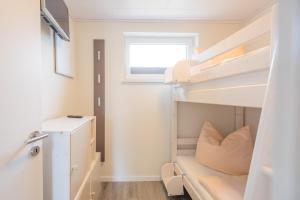 a small bedroom with bunk beds and a window at Bungalow Neuwarft, Wohnung 2 in Dagebüll +1 photo