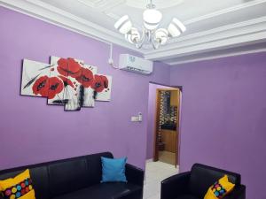 a living room with purple walls and a black couch at Residence Sighaka - Gold Apartment - WiFi, Gardien, Parking in Douala