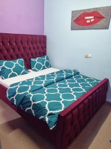 a bed with a red headboard and blue sheets and pillows at Residence Sighaka - Gold Apartment - WiFi, Gardien, Parking in Douala