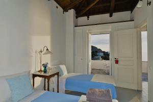 a bedroom with two beds and a door to a balcony at Villa Sunset Hydra in Hydra +71 photos
