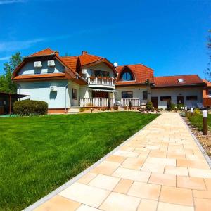 a house with a brick walkway in front of a yard at Pál Villa - Premium Apartments - Kecskemét in Kecskemét
