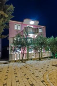 a pink building with trees in front of it at Villa Magica in Pirovac