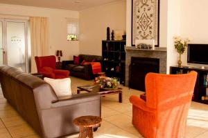 sala de estar con sofá, sillas y chimenea en Amohela Guesthouse en Midrand