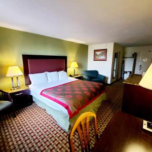 ein Hotelzimmer mit einem großen Bett und einem Stuhl in der Unterkunft Town Inn in Bordentown