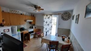 a kitchen with a table and a clock on the wall at Apartment PinoAppLosinj in Veli Lošinj