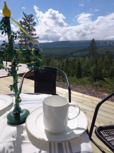 a white coffee cup sitting on a table with a view at Mysig lägenhet med fjällutsikt i Sälen in Sälen