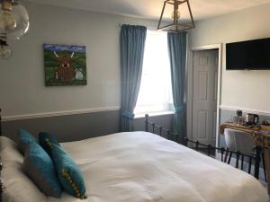 a bedroom with a bed with blue pillows and a window at The Black Bull Inn in Middleham