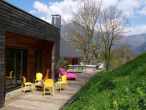 une terrasse en bois avec des chaises jaunes et une table dans l'établissement Le Baluchon, à Cierp