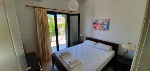 a bedroom with a bed with white sheets and a window at Sivota Apartments in Syvota