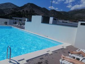 ein Pool mit zwei Personen, die nebeneinander auf Stühlen sitzen in der Unterkunft Trebinje Star in Trebinje
