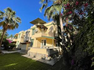 a yellow house with palm trees in front of it at VILLA KONAK CLUB in Alanya
