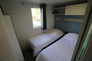 two beds in a small room with a window at Loggia Camping Belle-Vue 2000 in Berdorf