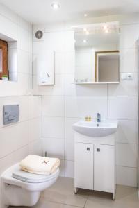 biała łazienka z toaletą i umywalką w obiekcie Domek letniskowy Słowiańska 15 w mieście Giżycko