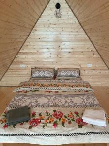 Ce lit se trouve dans un dortoir doté d'un mur en bois. dans l'établissement Conacul lui Patrick, à Poenari